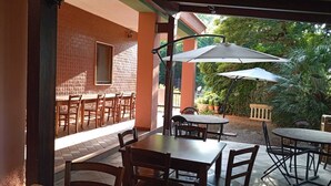 An outdoor patio area with tables and chairs, a covered seating area, and a view of greenery. - Casa vacanza la sorgente  (Corigliano-Rossano)