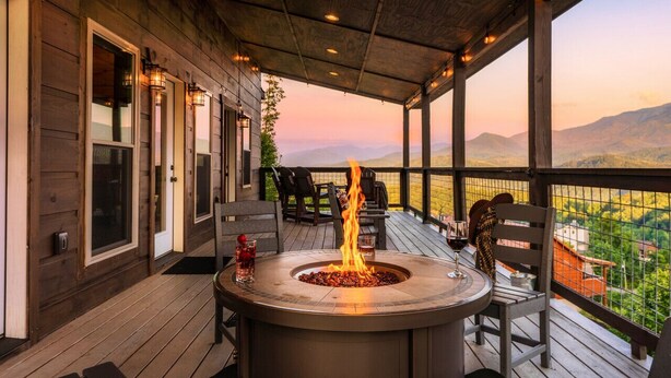 A covered outdoor patio with a fire pit, seating, and a view of the mountains. - VIEWS/YARD/Hot Tub/Theater/Game Room - Wild Ginger (Gatlinburg)