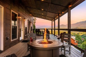 Un patio exterior cubierto con una chimenea, asientos y vistas a las montañas.