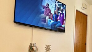 A television mounted on a wall above a wooden console table with decorative items.