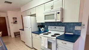 A kitchen with white cabinets, a microwave, a stove, and a refrigerator.