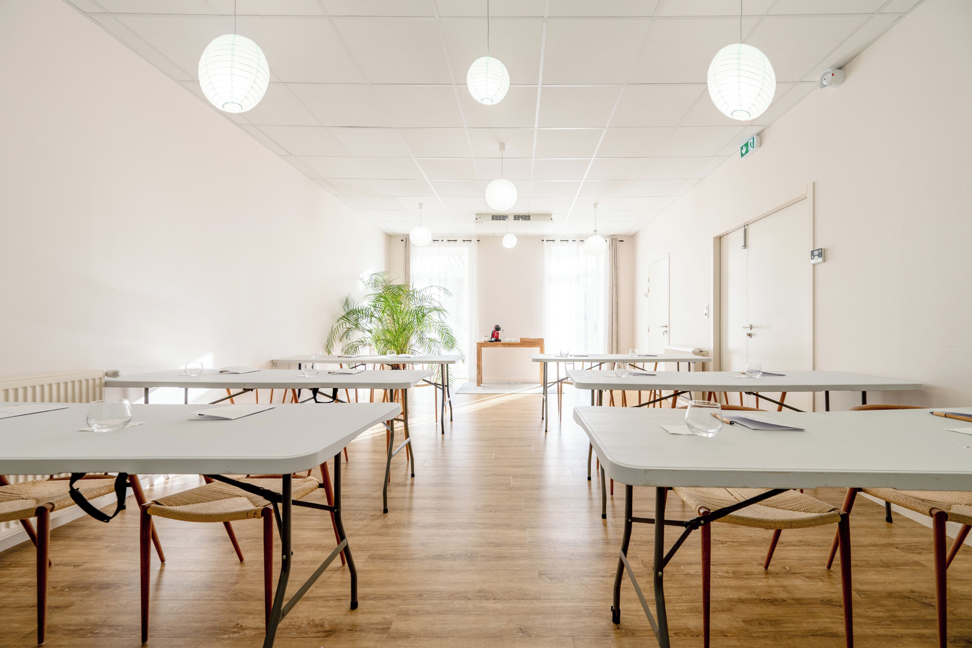 Ein Konferenzraum mit weißen Tischen, Stühlen und einer Pflanze.