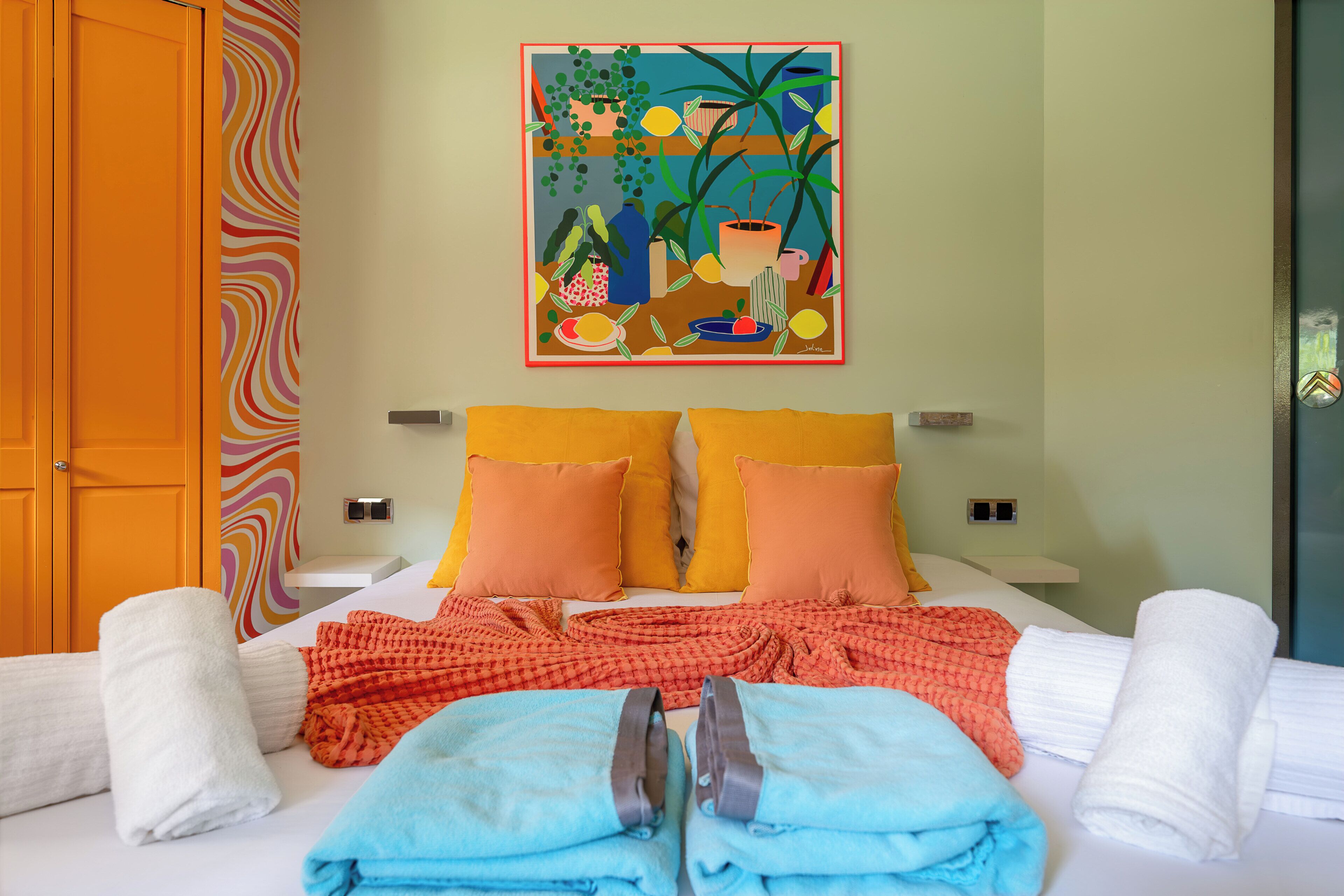 Une chambre d’hôtel avec un lit, des oreillers, des serviettes, un tableau et une porte.
