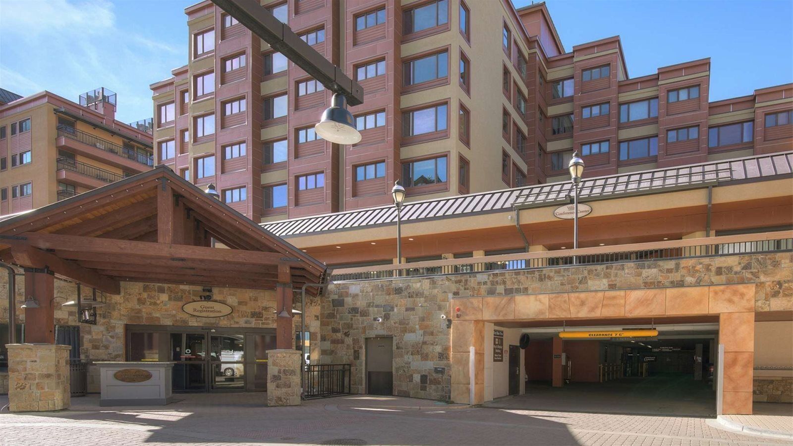 A hotel entrance with a stone facade, a guest registration desk, and a covered walkway leading to the building.