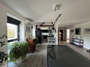 A spacious living area with a dining table, kitchen in the background, and large windows. - Loft near downtown (Nevers)