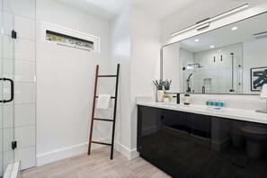 A modern bathroom with a glass shower, a white vanity, and a large mirror.