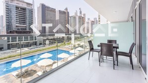 Eine moderne Wohnung mit Balkon mit Blick auf einen Pool und Stadtpanorama.