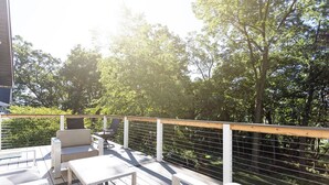 Eine Terrasse im Freien mit weißer Möbel, darunter ein Sofa und ein Tisch, umgeben von einem Holgitter.