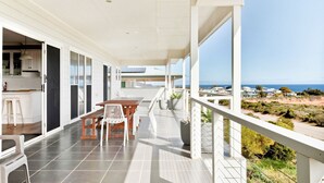 A modern balcony with a dining area, a kitchen, and a view of the ocean.