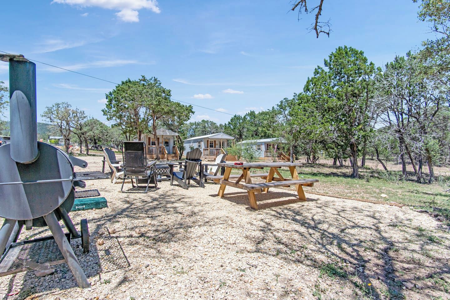 Un camping con mesas de picnic, sillas y una parrilla.