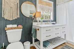 A bathroom with a toilet, sink, vanity, and a mirror.