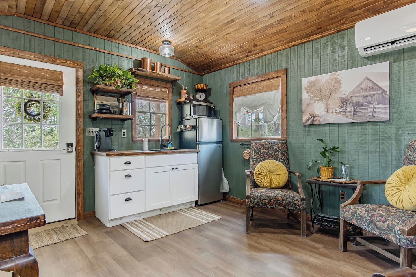 A rustic kitchen with wooden cabinets, a refrigerator, and a microwave.