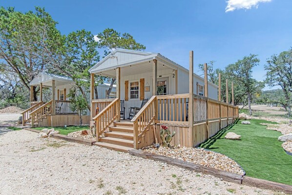 A two-story wooden cabin with a covered porch and a staircase leading to the entrance.