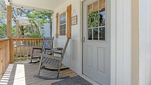 A wooden porch with a rocking chair and a bench, a white door with a window, and a welcome sign. - Lucky Star Ranch - Stargazer (Bandera)