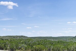 A landscape with a clear sky and a hilly terrain covered with dense vegetation. - Lucky Stargazer Cabin 2 | 1BR with Animals & Views (Bandera)
