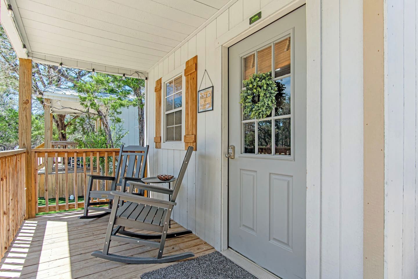 A porch with a rocking chair, a small table, and a door with a window.