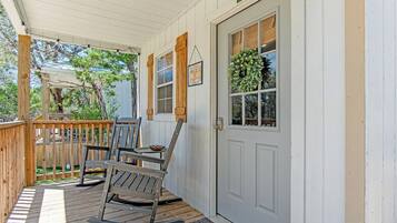 A porch with a rocking chair, a small table, and a door with a window.