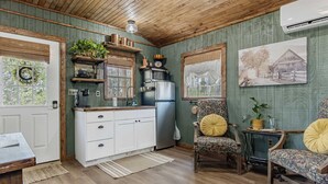 A cozy kitchen with wooden cabinets, a refrigerator, and a dining area with floral-patterned chairs. - Lucky Star Ranch - Stargazer (Bandera)