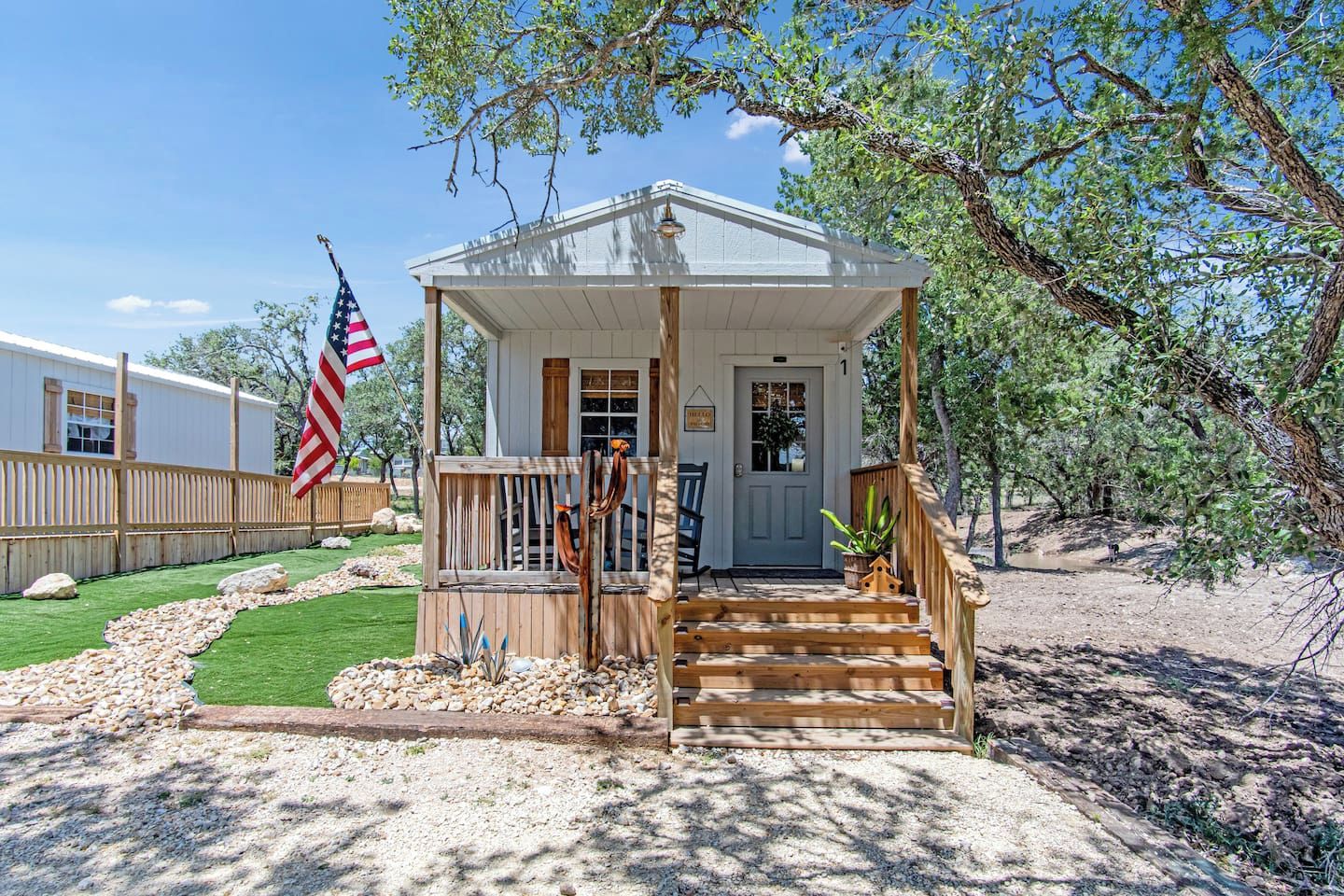 A small wooden structure with a porch, a flag, and a door.