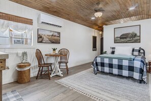 A room with a bed, a dining table with chairs, a small table with a plant, and a hanging light fixture. - Lucky Shooting Star #3 | Romantic Stay Near Parks (Bandera)