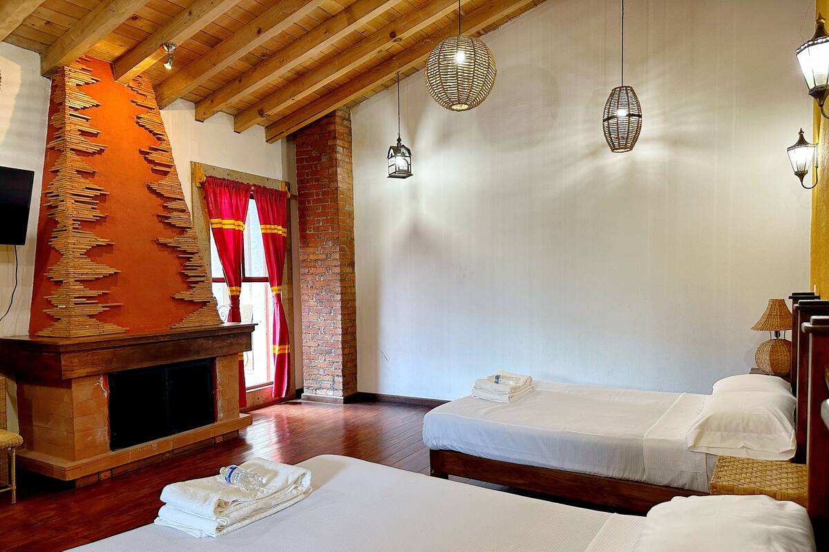 A hotel room with two beds, a fireplace, and hanging lanterns.