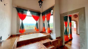 Un baño con bañera, piso de baldosas y cortinas.