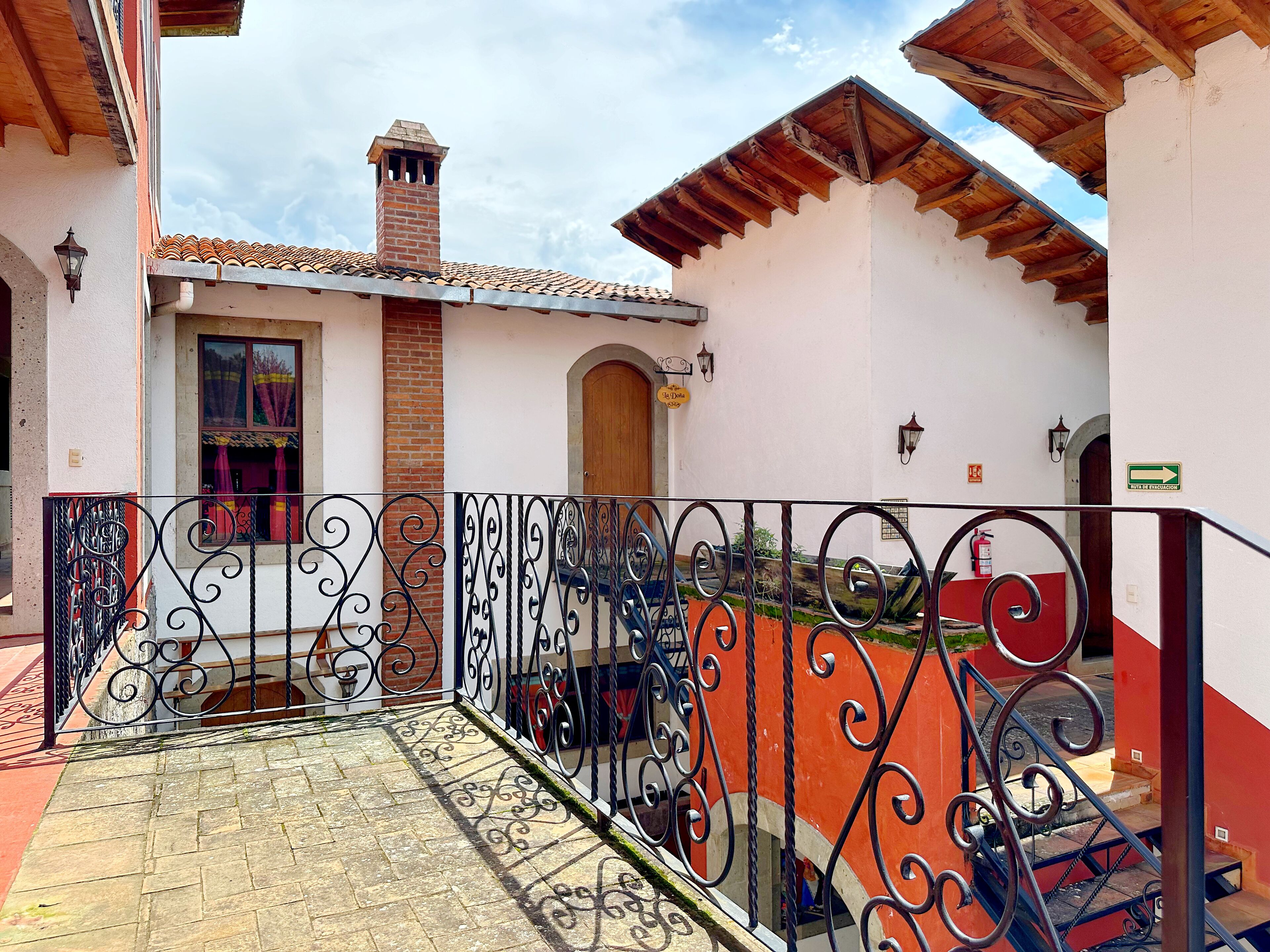 A courtyard with a tiled floor, a wrought iron fence, and a brick chimney.