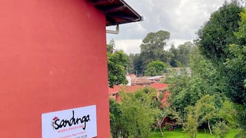 Ein rotes Gebäude mit einem Schild für 'Sandinga Suites Patezcuaro' und einem gepflegten Garten mit verschiedenen Pflanzen und einem Weg.