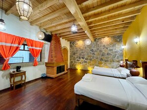 A room with wooden beams, a stone wall, a fireplace, and two beds. - Sandunga Suites Patzcuaro (Patzcuaro)