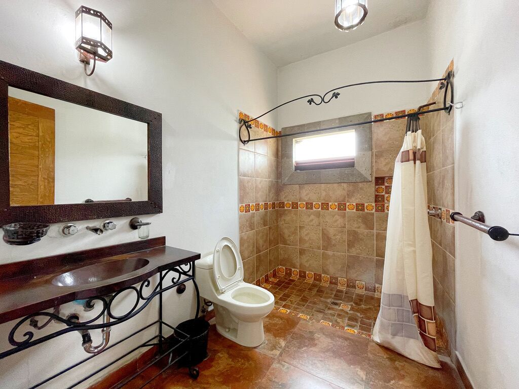 A bathroom with a wooden vanity, a white toilet, a shower with a glass door, and a tiled shower area.