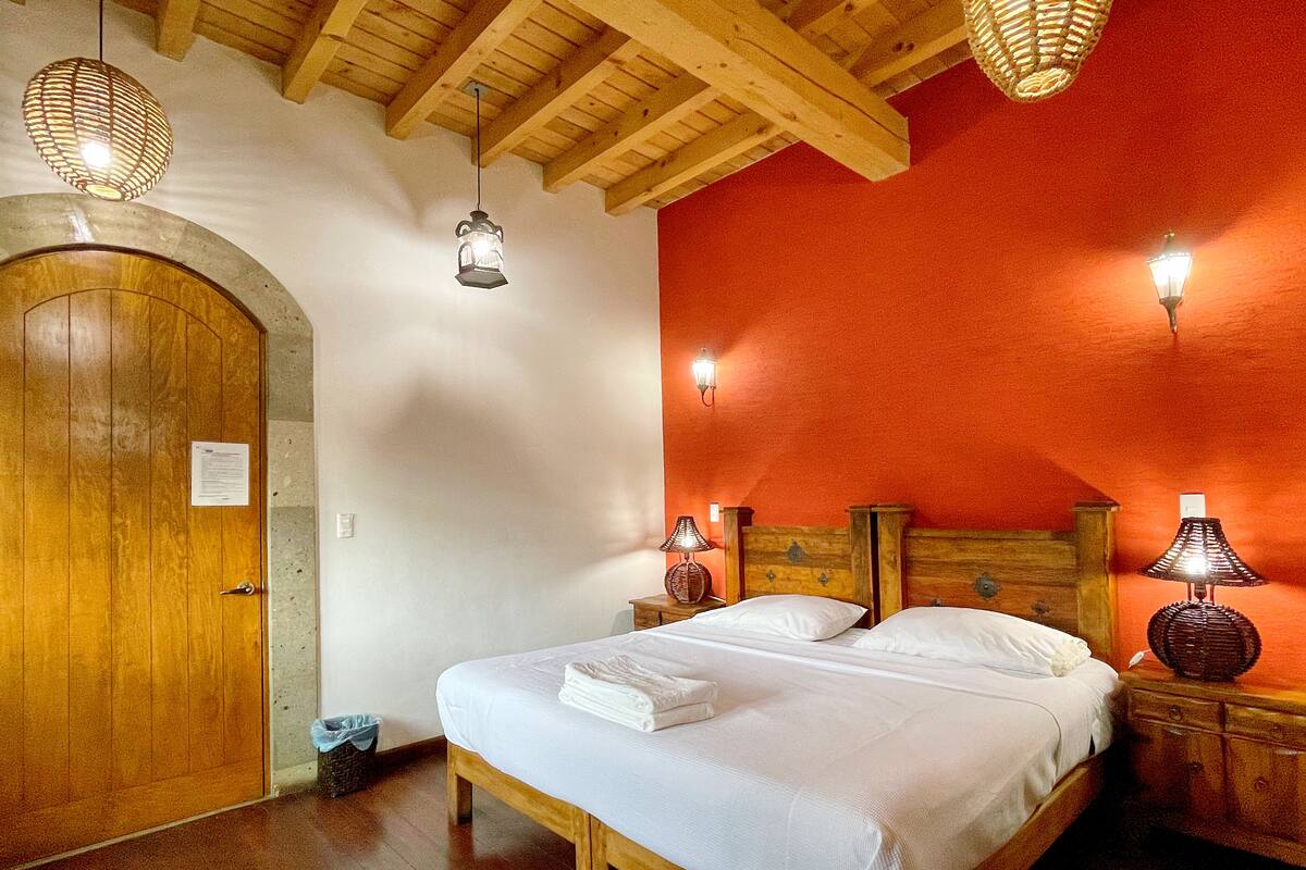 A bedroom with a wooden bed, a wooden door, and a red wall.