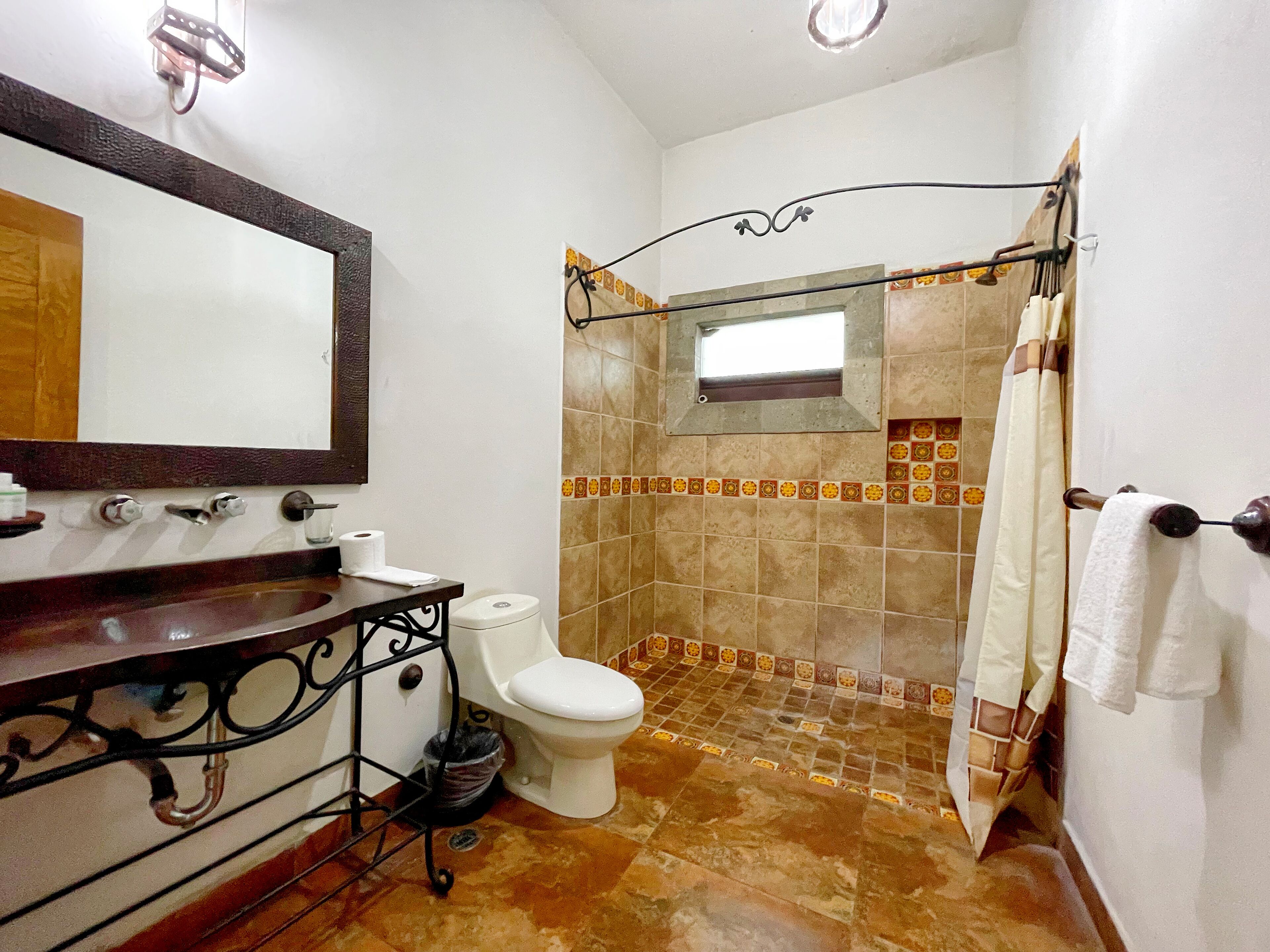 A bathroom with a toilet, sink, and shower area.