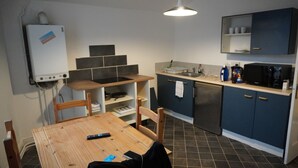A compact kitchen with a dining table, chairs, a microwave, and a refrigerator.