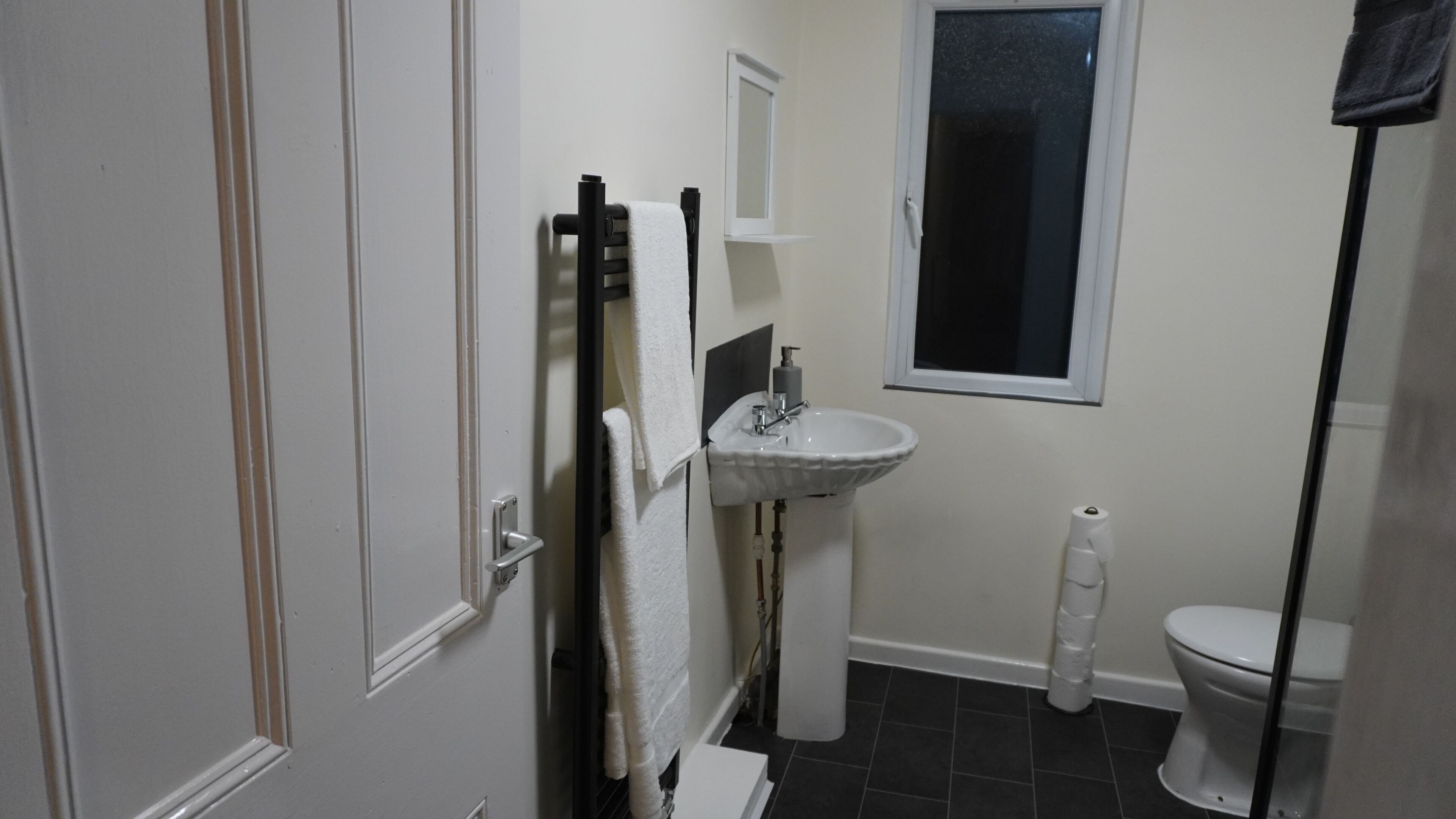 A bathroom with a white sink, a toilet, and a window.
