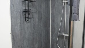 A modern shower area with a glass door, a metal towel rack, and a showerhead.