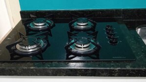 A kitchen with a four-burner stove, white cabinetry, and a teal backsplash. - Apar Aconchegante no Centro de Curitiba  (Curitiba)