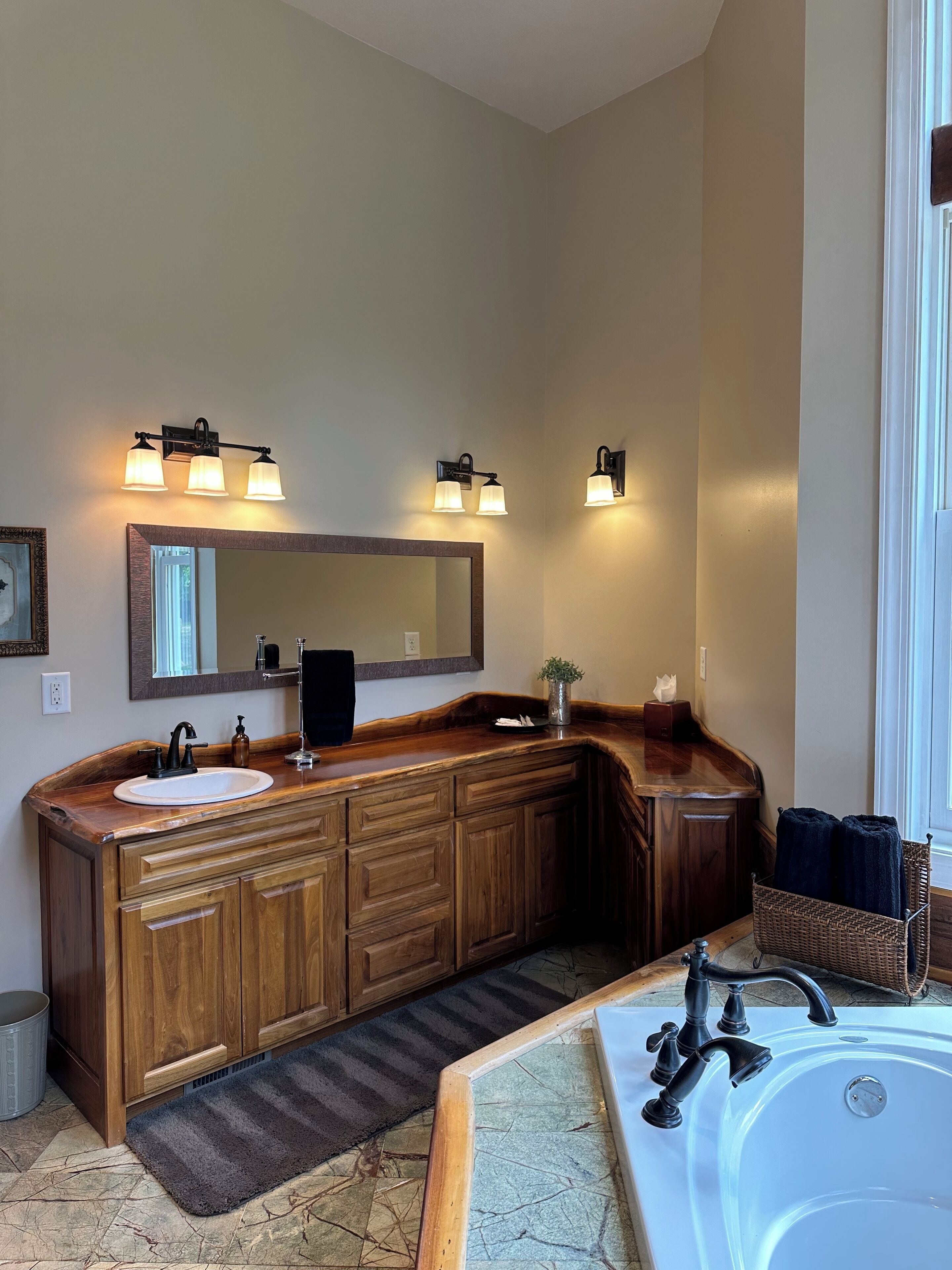 A bathroom with a wooden vanity, two sinks, a large mirror, and a bathtub.