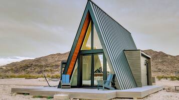 A modern, triangular-shaped building with a glass facade, situated in a desert landscape.