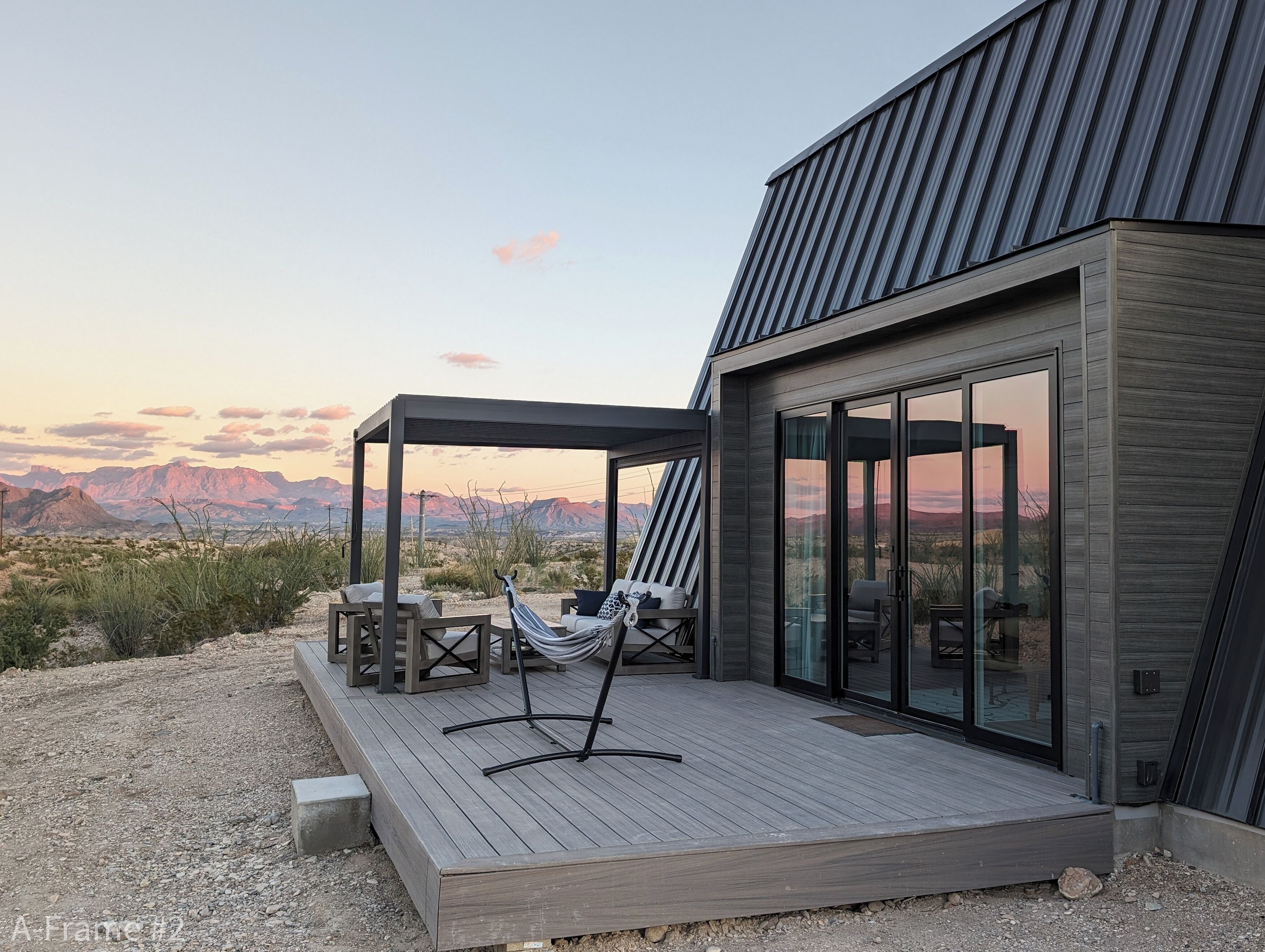 Una casa moderna con terraza, hamaca y vistas a las montañas.