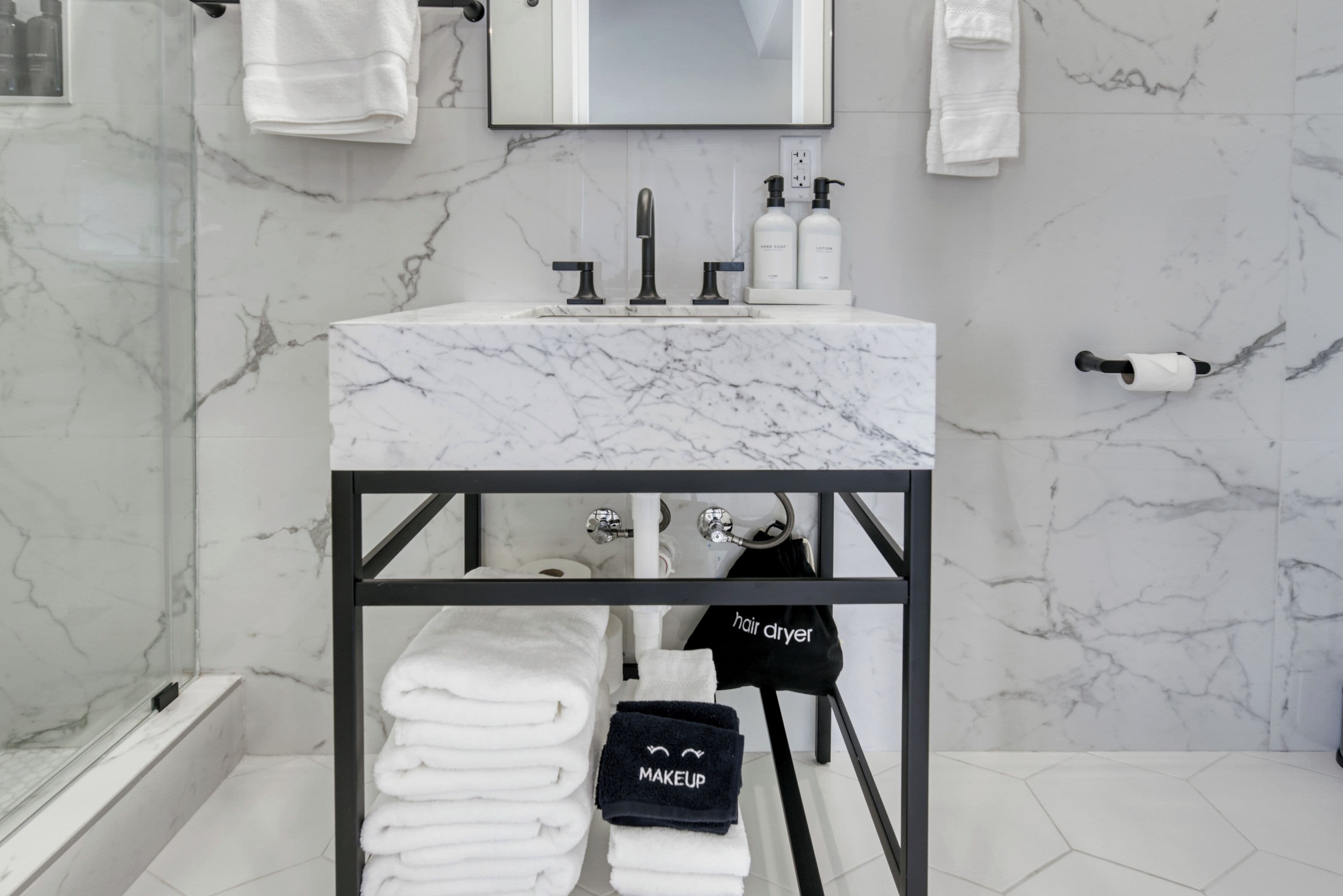 A bathroom with a marble sink, a hair dryer, and neatly folded towels.