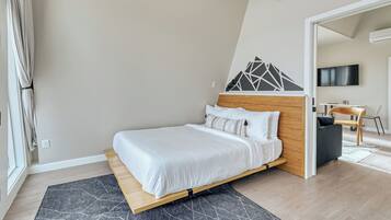 Une chambre moderne avec un lit en bois, un tapis à motifs gris et un téléviseur dans un coin.
