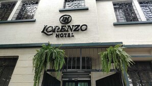 Das Lorenzo Hotel mit Schilder über dem Eingang, zwei hängenden Pflanzen und Gitterfenstern.