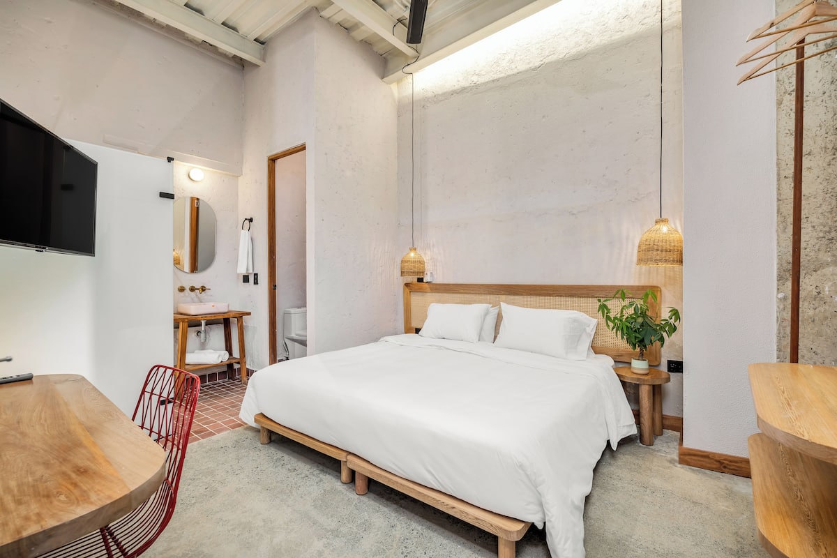 A bedroom with a wooden bed, a TV, a small table, and a chair.
