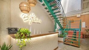 A reception desk with a sign reading "Botanica Casa Hotel," a staircase, and potted plants. - Botánica Manila by HOUSY HOST (Medellín)