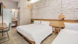 A modern hotel room with a large bed, a wooden nightstand, a small stool, a desk with a chair, and a bathroom with a mirror and sink. - Botánica Manila by HOUSY HOST (Medellín)