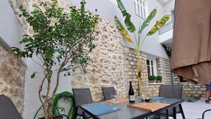Un espacio de estar al aire libre con un muro de piedra, una mesa con sillas y una planta en maceta.