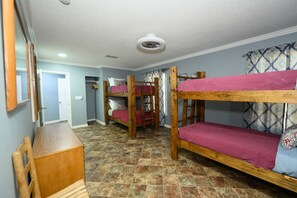 A room with bunk beds, a wooden desk, and a patterned curtain.