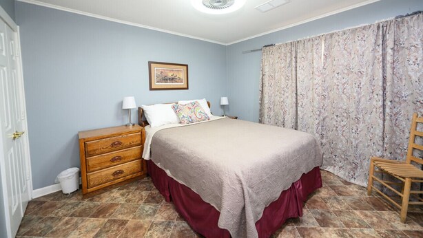 Une chambre à coucher avec un lit, une commode, une chaise et un tableau au mur.