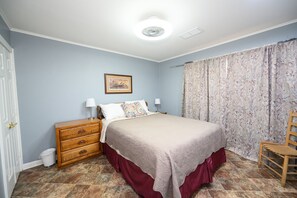 Ein Schlafzimmer mit Bett, Schminktisch, Stuhl und einem Bild an der Wand.