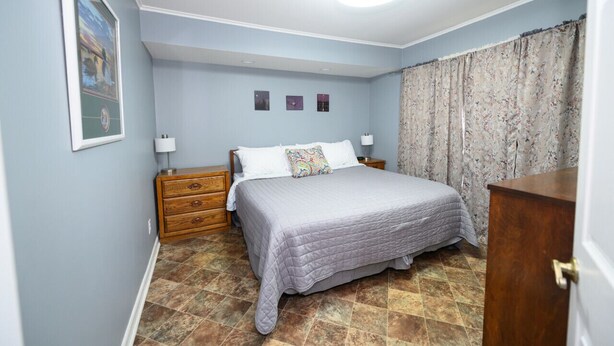 Une chambre à coucher avec un lit, des tables de chevet, une commode et un luminaire au plafond.